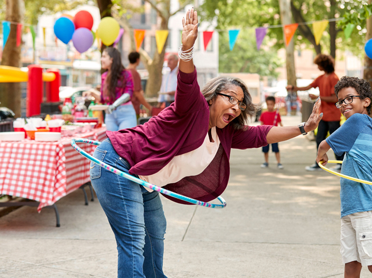 Grandmother hoola-hoops with her grandson at street fair