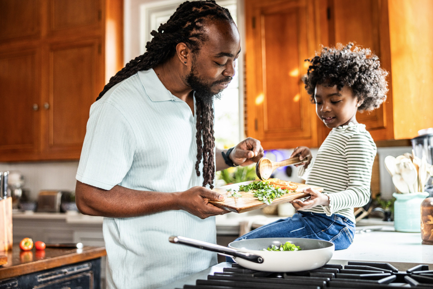 Un padre cocinando con su hijo.