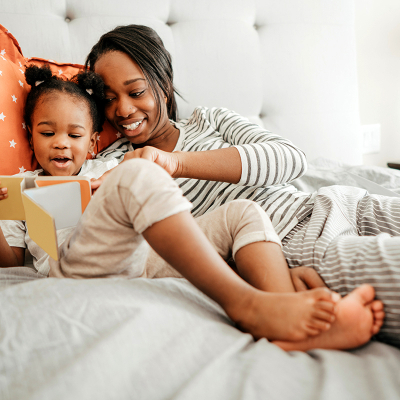 A woman and young child reading a book in bed