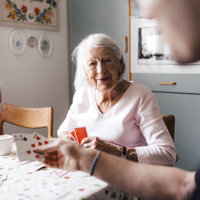 An elderly woman playing cards with a person