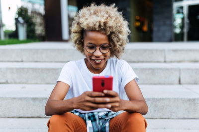 A women on her phone sitting on stairs outside